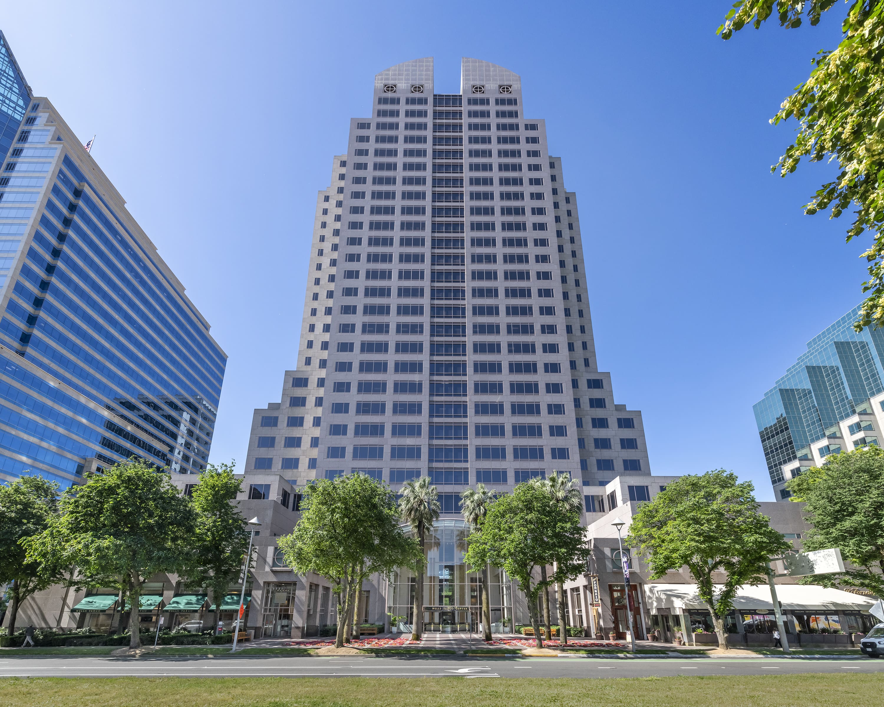 High-rise office building surrounded by trees and nearby structures.